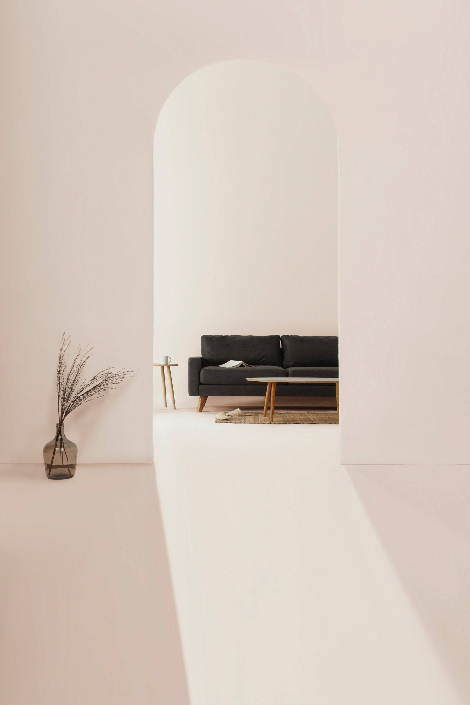 A living room with a black couch and a vase of flowers.