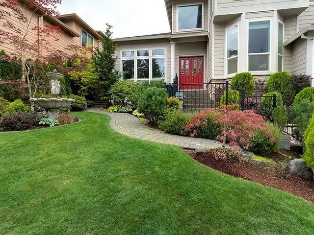 A large house with a lush green lawn and a walkway leading to it.