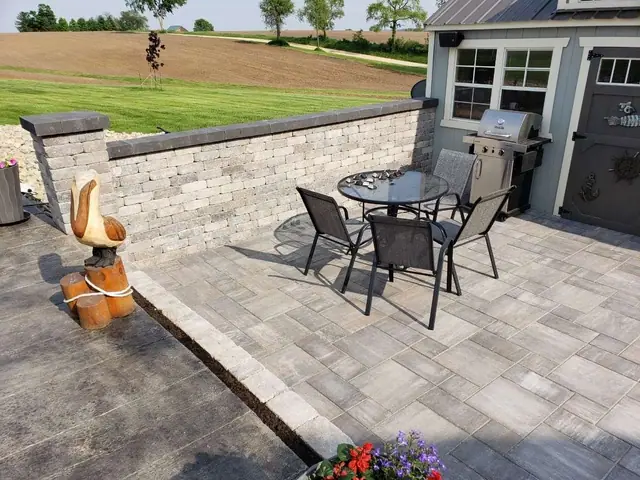 A patio with a table and chairs and a grill.
