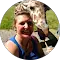 A woman is standing next to a giraffe in a circle.