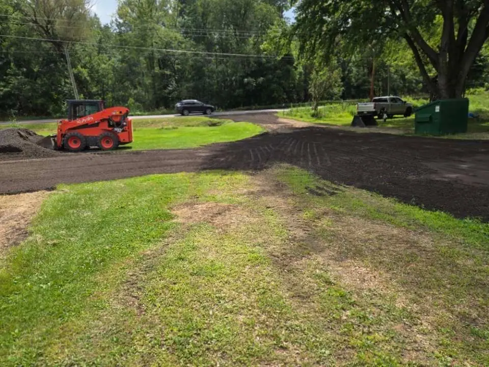 A red skid steer is sitting in the middle of a grassy field.